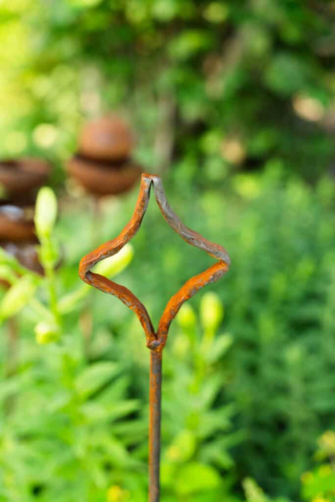 Rustikusan kialakított fém kerítésdísz, kert dekoráció, kültéri design, természetes kertélmény.