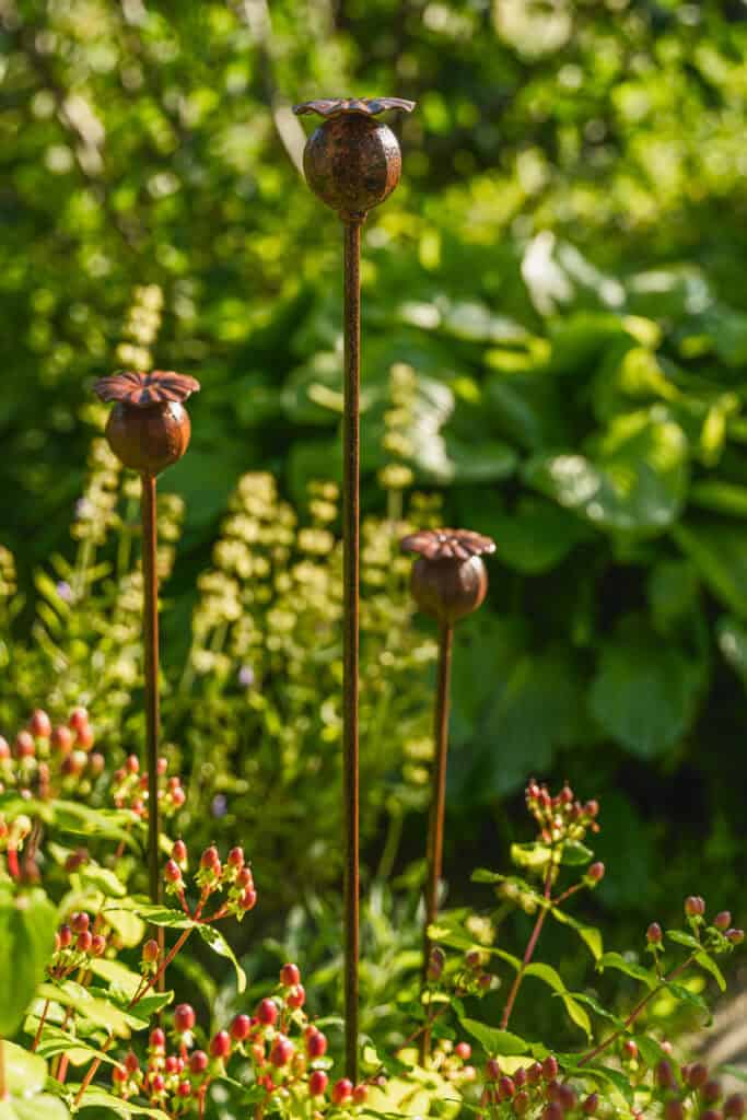 Szépen megmunkált, rozsdás vasszobrok díszítik a növények között a kertet.
