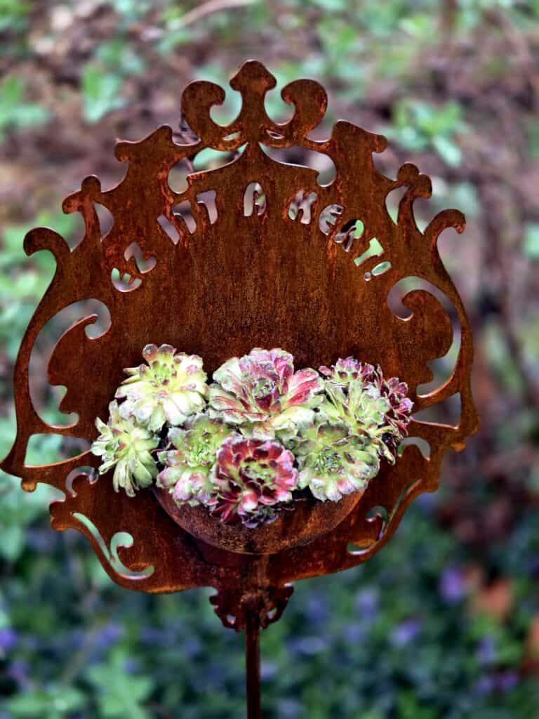 Rozsdamentes kertiposta virágokkal, díszes kertészeti dekoráció.